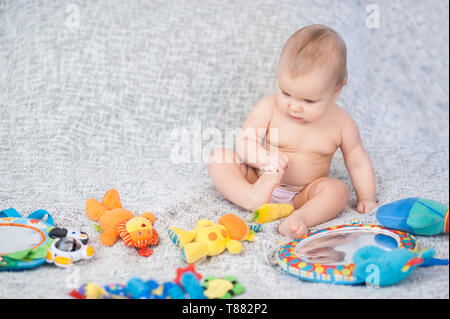 Il bambino che giace sul tappeto di sviluppo. giocando in Mobile. giocattoli educativi. Dolce bambino gattona e giocare con i giocattoli sul tappeto. Foto Stock