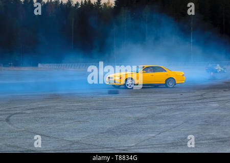 Sfocata immagine di diffusione deriva di gara di auto con un sacco di fumo dalla combustione di pneumatici su pista di velocità. Foto Stock