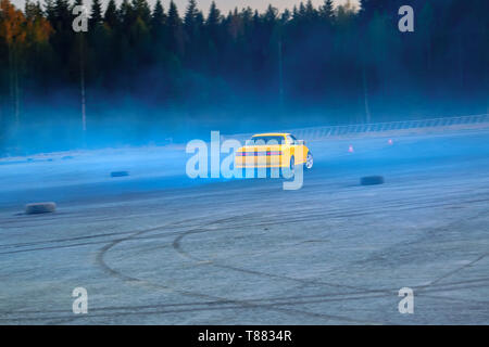 Sfocata immagine di diffusione deriva di gara di auto con un sacco di fumo dalla combustione di pneumatici su pista di velocità. Foto Stock