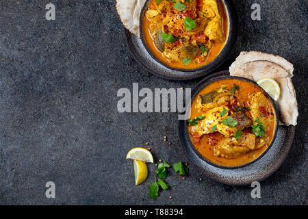 Cibo indiano. Tradizionale del Kerala, pesce al curry con pane naan, lastra grigia, sfondo nero Foto Stock