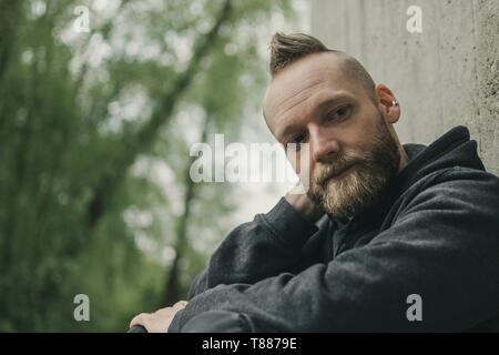 Felice soddisfatto giovane uomo seduto per terra e di pensiero Foto Stock