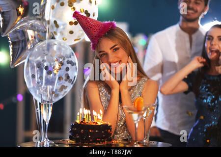 Giovane donna vicino la sua torta di compleanno a parte nel club Foto Stock