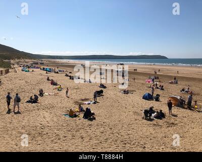 Vacanzieri godere il sole a Woolacombe in North Devon, come le temperature sono impostati per salire nuovamente dopo una settimana di brutto tempo. Foto Stock