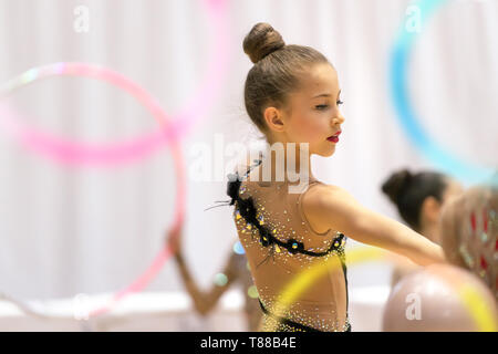 Piccola e bella ragazza ginnasta esegue una danza con un cerchio, sano ed attivo infanzia, sport, prendendo parte a una ginnastica ritmica della concorrenza Foto Stock