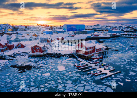 Tramonto sul mare ghiacciato e il villaggio di pescatori di Ballstad, Vestvagoy, Isole Lofoten in Norvegia Foto Stock