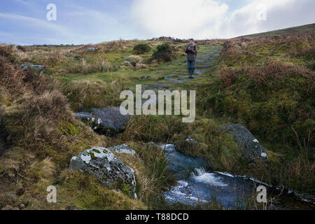 La ragazza scatta una fotografia sul percorso fino all'antico insediamento di Grimspound, da un piccolo ruscello chiamato Grim's Lake, Dartmoor, Devon, Regno Unito. MODELLO RILASCIATO Foto Stock