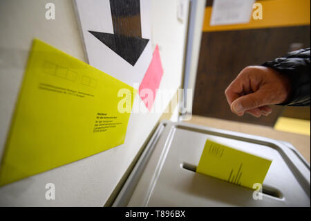 Stuttgart, Germania. Il 10 maggio, 2019. Un uomo getta una lettera di ballottaggio per le elezioni locali nel Baden-Württemberg in un urna. Credito: Sebastian Gollnow/dpa/Alamy Live News Foto Stock