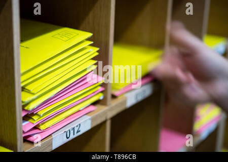 Stuttgart, Germania. Il 10 maggio, 2019. Illustrazione - Una donna mette una lettera elettorale per le elezioni locali nel Baden-Württemberg (giallo) su un ripiano. In aggiunta vi sono lettere elettorale per le elezioni europee (rosa). Credito: Sebastian Gollnow/dpa/Alamy Live News Foto Stock