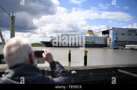 Papenburg (Germania). Il 12 maggio 2019. Un uomo fotografie della nave da crociera "spirito di scoperta' con il suo telefono cellulare come egli lascia il cantiere navale Meyer Werft la costruzione di dock. "Lo spirito di scoperta' è 236 metri di lunghezza e poco più di 31 metri di larghezza. Credito: Carmen Jaspersen/dpa/Alamy Live News Foto Stock