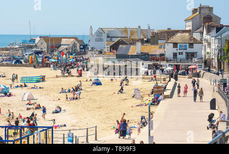 Lyme Regis, Dorset, Regno Unito. Il 12 maggio 2019. Regno Unito: Meteo visitatori e amanti di spiaggia godetevi la pittoresca spiaggia presso la località balneare di Lyme Regis su una calda e soleggiata domenica. Le temperature sono dilagano con alti di 25 gradi celsius previsioni per la prossima settimana. Credito: Celia McMahon/Alamy Live News. Foto Stock