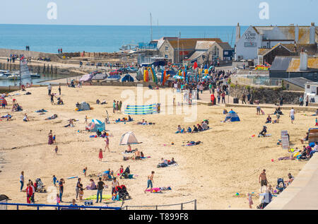 Lyme Regis, Dorset, Regno Unito. Il 12 maggio 2019. Regno Unito: Meteo visitatori e amanti di spiaggia godetevi la pittoresca spiaggia presso la località balneare di Lyme Regis su una calda e soleggiata domenica. Le temperature sono dilagano con alti di 25 gradi celsius previsioni per la prossima settimana. Credito: Celia McMahon/Alamy Live News. Foto Stock