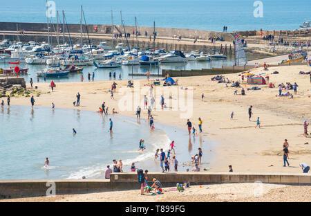 Lyme Regis, Dorset, Regno Unito. Il 12 maggio 2019. Regno Unito: Meteo visitatori e amanti di spiaggia godetevi la pittoresca spiaggia presso la località balneare di Lyme Regis su una calda e soleggiata domenica. Le temperature sono dilagano con alti di 25 gradi celsius previsioni per la prossima settimana. Credito: Celia McMahon/Alamy Live News. Foto Stock