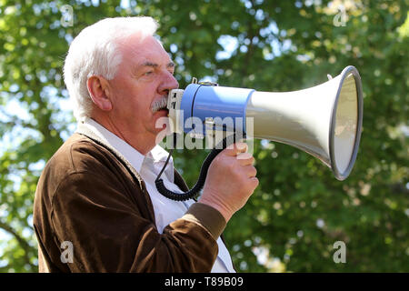 Larz, Germania. Il 12 maggio 2019. Hartmut Lehmann, sindaco del comune di Lärz, parla in un rally per la conservazione della cultura e della musica festival 'Fusion'. Circa un centinaio di persone hanno protestato domenica in Lärz (Meclemburgo Lake District) contro una stazione di polizia e pattuglie di polizia presso l'alternativa 'Fusion' festival. Credito: dpa picture alliance/Alamy Live News Foto Stock