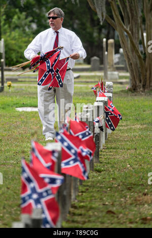 Charleston, STATI UNITI D'AMERICA. 11 Maggio, 2019. Un confederato discendente raccoglie le bandiere di battaglia da grave marker durante il Confederate Memorial Day al Cimitero di magnolia 11 Maggio 2019 a Charleston, Carolina del Sud. Confederate memorial day continua ad essere uno stato ufficiale holiday in Carolina del Sud dove la Guerra Civile Americana ha iniziato a. Credito: Planetpix/Alamy Live News Foto Stock