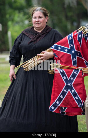 Charleston, STATI UNITI D'AMERICA. 11 Maggio, 2019. Un membro delle Nazioni Figlie della Confederazione, vestito in costume, raccoglie le bandiere di battaglia da grave marker durante il Confederate Memorial Day al Cimitero di magnolia 11 Maggio 2019 a Charleston, Carolina del Sud. Confederate memorial day continua ad essere uno stato ufficiale holiday in Carolina del Sud dove la Guerra Civile Americana ha iniziato a. Credito: Planetpix/Alamy Live News Foto Stock