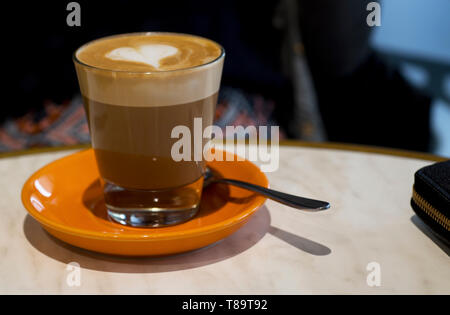 Latte caffè con una a forma di cuore la schiuma in un caffè di vetro. Foto Stock