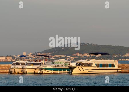 Francia, Herault, Meze, imbarcazioni turistiche al fianco di un molo con il Mount Saint-Clair in background Foto Stock