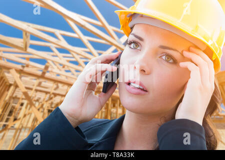 Interessato contraente femmina in Hard Hat tramite telefono cellulare al sito in costruzione. Foto Stock