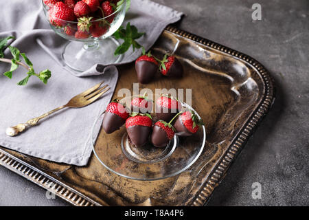 Vassoio con gustoso cioccolato fragole immerse sulla tabella grigia Foto Stock