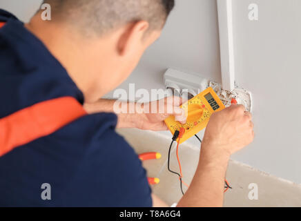 Elettricista misurando la tensione nella presa in ambienti interni Foto Stock