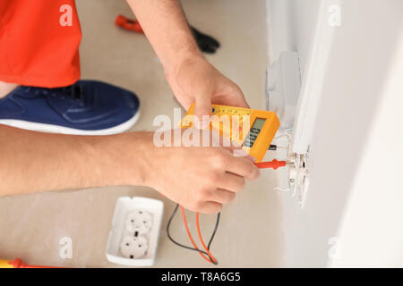 Elettricista misurando la tensione nella presa in ambienti interni Foto Stock