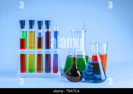 Vetreria di laboratorio con liquidi diversi su sfondo chiaro Foto Stock