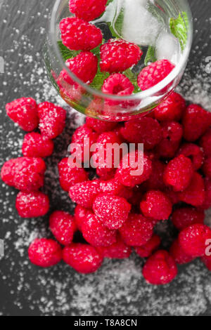 Freschi e deliziosi lamponi maturi con lo zucchero e la bevanda fredda sulla piastra di ardesia Foto Stock