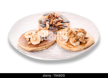 Piastra con gustosi pancake, noci e fette di banana su sfondo bianco Foto Stock