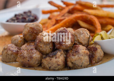 Polpette Kottbullar servito con patate dolci patatine fritte, insalata di cetrioli e salsa di lingonberry Foto Stock