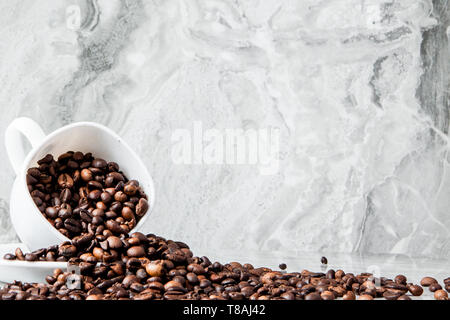 Nero caffè nella tazza e i chicchi di caffè su sfondo marmo. Vista superiore, lo spazio per il testo Foto Stock