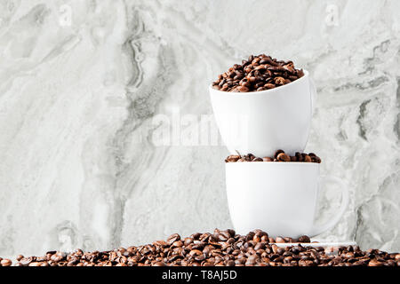 Nero caffè nella tazza e i chicchi di caffè su sfondo marmo. Vista superiore, lo spazio per il testo Foto Stock