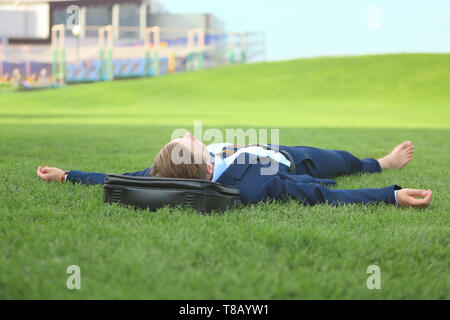 Giovane uomo in abiti formali relax su erba verde all'aperto Foto Stock