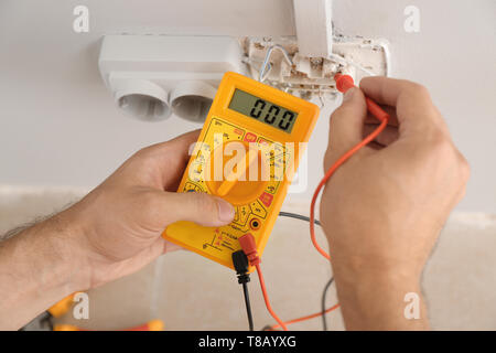 Elettricista misurando la tensione nella presa in ambienti chiusi, primo piano Foto Stock