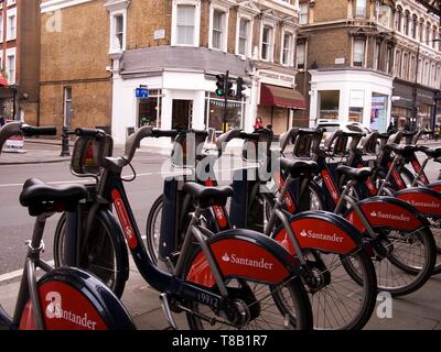 Una fila di biciclette a noleggio con la pubblicità da Banco Santander nelle loro gabbie docking in London, England, Regno Unito Foto Stock