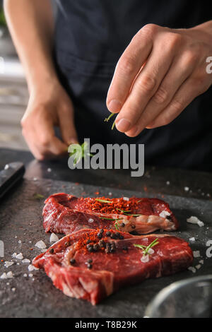 L'uomo la preparazione di carne in cucina Foto Stock