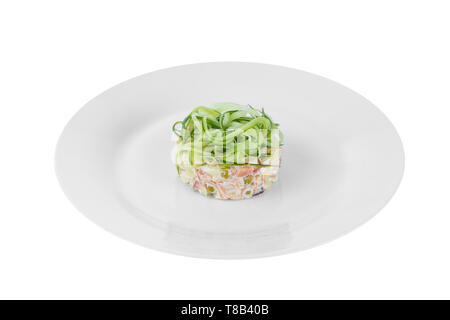 Insalata russa con paglia dal cetriolo, piselli, carote, patate su piastra bianca di sfondo isolato, vista laterale Foto Stock