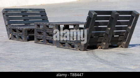 Tavolo e sedie di pallet sul marciapiede, verniciato in nero il concetto di arredo urbano Foto Stock