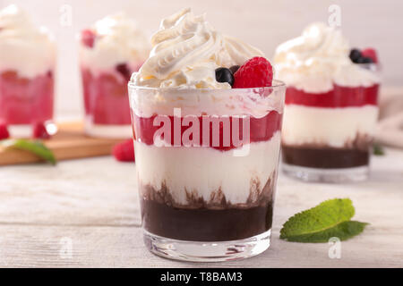 Deliziosi dessert con frutti di bosco in vetro su un tavolo di legno Foto Stock