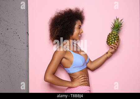 Bella donna afro-americana con ananas sul colore di sfondo Foto Stock