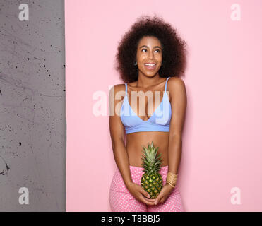 Bella donna afro-americana con ananas sul colore di sfondo Foto Stock