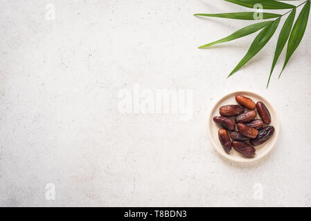 Date dei frutti su piastra su sfondo bianco, vista dall'alto, copia dello spazio. Fase organica essiccata date frutti. Foto Stock