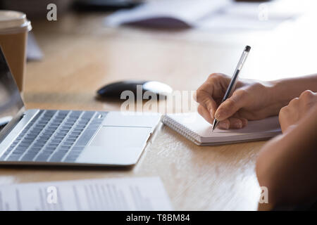 Close up mani femminili tenendo pen la scrittura nel blocco note Foto Stock