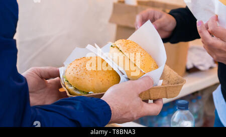 L'uomo prendendo gli hamburger a street food festival Foto Stock