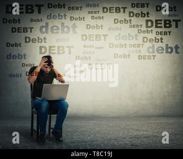 Sconvolto e ha sottolineato giovane uomo utilizzando laptop seduto su una sedia, tenendo le mani alla testa, presenta scossa emotiva circa enormi quantità di debito. Deluso freelance Foto Stock