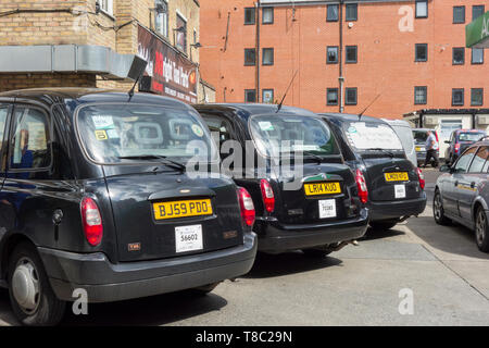 Una fila di Londra taxicabs nero in un garage a Southwark, Londra, Regno Unito Foto Stock