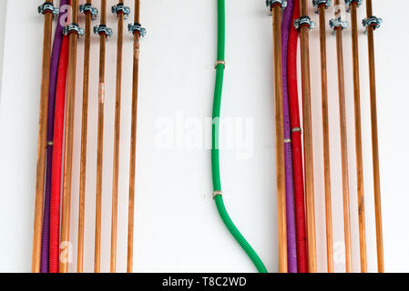 Tubi in rame e colorate di tubi in plastica per il cablaggio elettrico su una parete bianca in corrispondenza di un edificio incompiuto sito Foto Stock