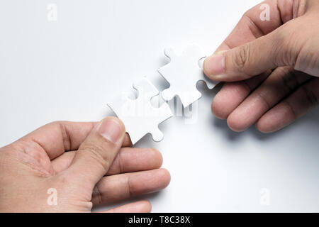 Il concetto di partenariato con le mani per mettere i pezzi del puzzle insieme Foto Stock