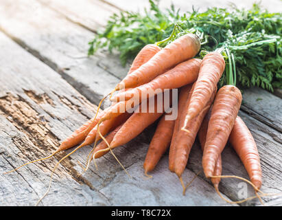 Mazzo di carote fresche liberamente giacente sul vecchio giardino board Foto Stock