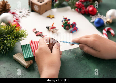 Bambino rendendo decorazioni di Natale da plastilina a tavola Foto Stock