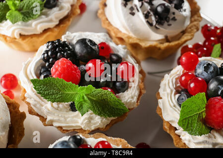 Gustose tortine con panna montata e frutti di bosco su tavola, primo piano Foto Stock